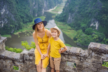 Mother and son tourists on the lake Tam Coc and pagoda of Hang Mua temple, Ninh Binh, Viet nam....