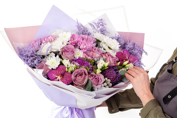 Woman florist in uniform hold a big flowers bouquet of purple roses.