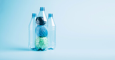 Plastic recycling and reuse concept. Empty plastic bottle and polyester fiber synthetic thread on a blue background.
