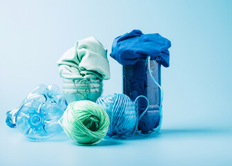 Empty plastic bottle and various fabrics made of recycled polyester fiber synthetic fabric on a...