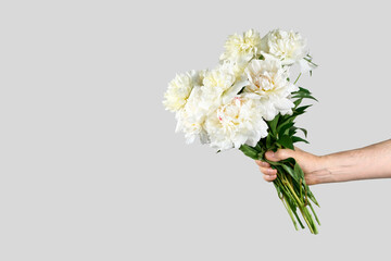 Male hand holds beautiful bouquet of white peonies. Flower delivery concept