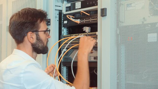 IT Engineer Patching Network Equipment In Server Room.Network Engineer Maintenance Work In Server Room .IT Technician Works With Ware And Cables in Big Data Center.Connecting Lan Cable To Mainframe