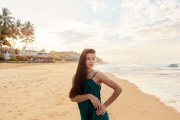 Fototapeta na wymiar Portrait of beautiful young woman in dress on the beach. Pretty girl on tropical beach. Freedom concept, holiday, beach, sky background.