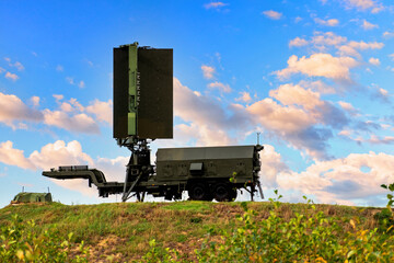 The mobile radar of military aviation stands on a hill against the background of a blue sky with...