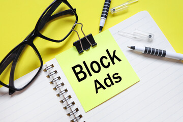 block ads. text on bright yellow sticker. on the blanket. yellow background and black glasses near...
