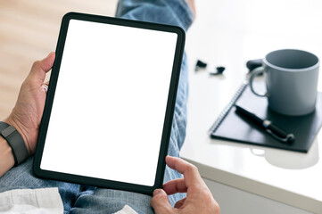 Cropped shot of man hands using tablet with blank screen while sitting in living room at home.