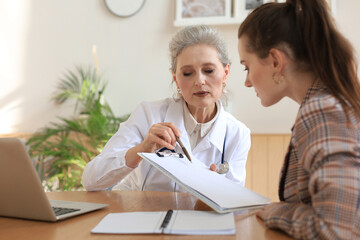 Middle aged female doctor therapist in consultation with patient in office.