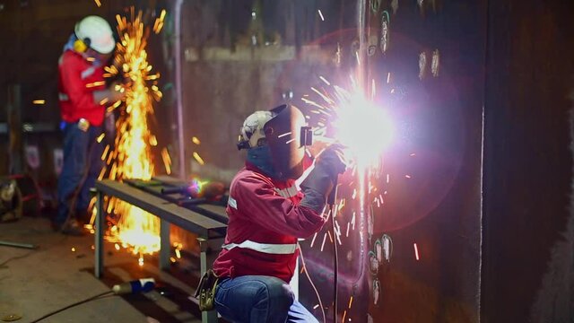 Welder metal and grinding carbon steel part joints shell plate inside tank confined space.