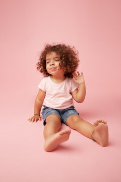 Charming kid sitting on pink background