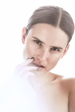 Freckled woman touching face with manicured hand
