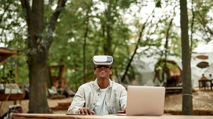 Smiling young man sitting in virtual reality glasses
