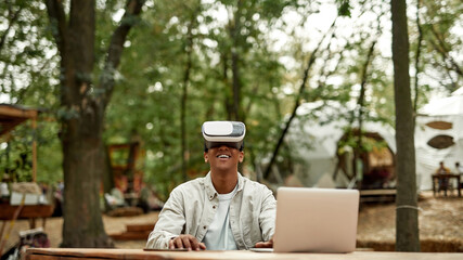 Fototapeta premium Smiling young man sitting in virtual reality glasses