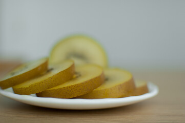 Slices of golden kiwi with yellow pulp on white plate on the kitchen. Exotic fruits, healthy eating concept