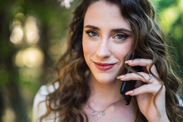 Smiling young woman using smartphone in lush park