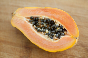 Fresh organic ripe papaya fruit cut in half on a wooden board. Exotic fruits, healthy eating concept