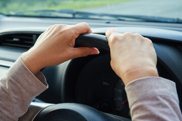 Woman's hands on the steering wheel, the driver is driving the car