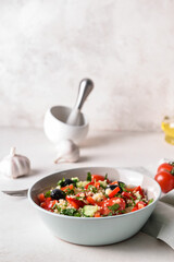 Bowl with couscous and vegetables on light background