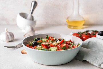 Bowl with couscous and vegetables on light background