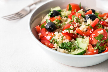 Bowl with couscous and vegetables on light background, closeup