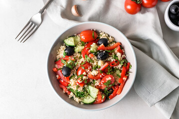 Bowl with couscous and vegetables on light background
