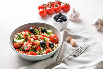 Bowl with couscous and vegetables on light background
