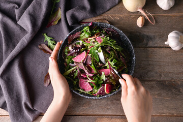 Woman eating tasty couscous with vegetables on wooden background