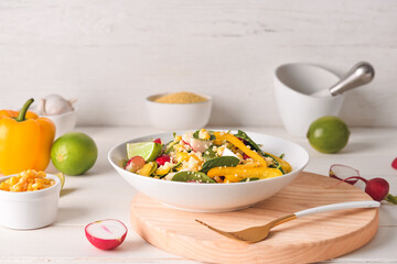 Bowl with couscous and vegetables on light wooden background