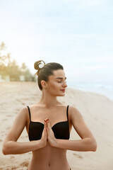 Beautiful woman practices yoga and meditates in the lotus position on th ebeach. Girl doing yoga. ...