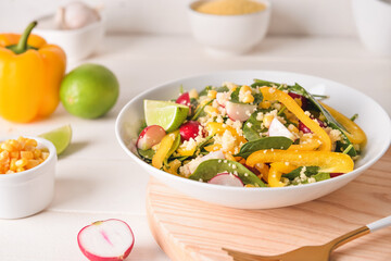 Bowl with couscous and vegetables on light wooden background, closeup