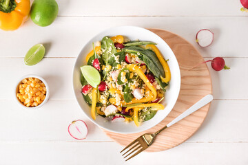 Bowl with couscous and vegetables on light wooden background