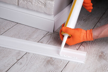 master applies glue to  skirting board with  glue gun