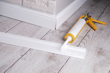 applying glue to the skirting board with a glue gun