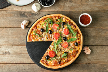 Board with tasty pizza and sauce on wooden background