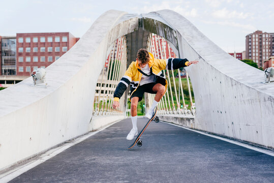 Caucasian teenager jumping with skateboard on the bridge in the city