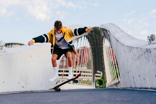 Caucasian teenager jumping with skateboard on the bridge in the city