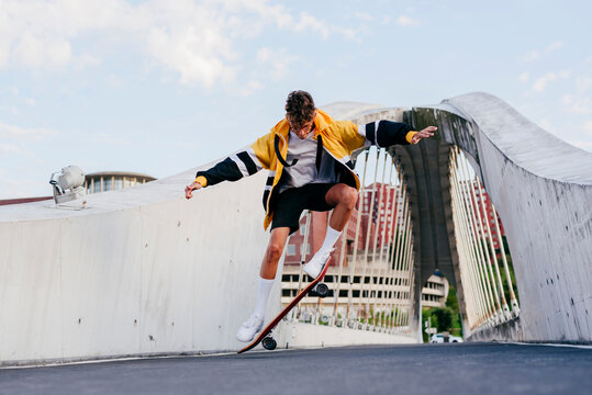 Caucasian teenager jumping with skateboard on the bridge in the city
