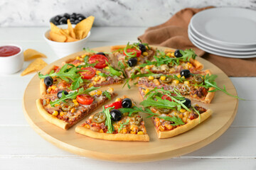 Board with slices of tasty pizza, sauce and nachos on light wooden background