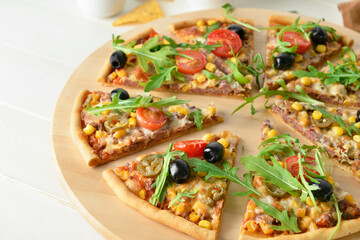 Board with slices of tasty pizza on light wooden background, closeup