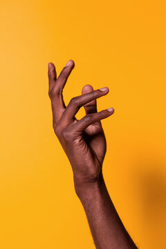 Black man raising hand against yellow background