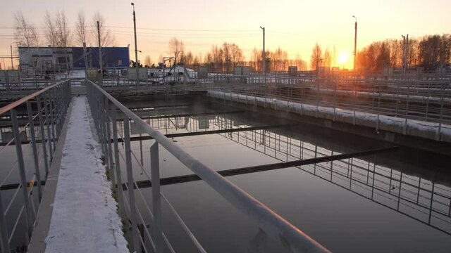 Empty snowy bridges over large reservoirs with processed water at purification station at sunset in winter evening