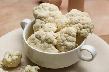 Bowl and plate with cauliflower cabbage on color background, closeup