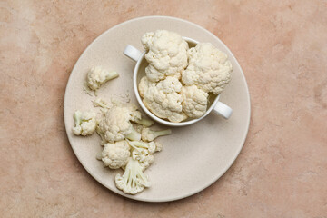 Bowl and plate with cauliflower cabbage on color background
