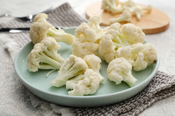 Plate with cauliflower cabbage on light grunge background, closeup