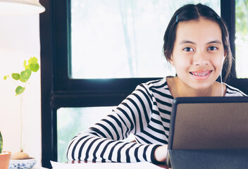 Girl wearing head set and studying online at home during home quarantine.
