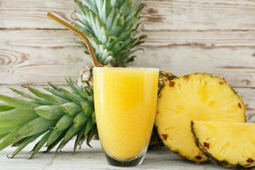 Glass of tasty pineapple smoothie on light wooden background