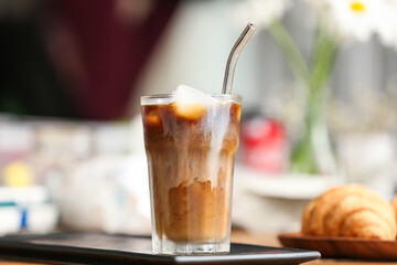 Glass of tasty ice coffee on table