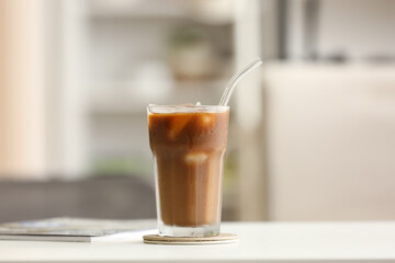 Glass of tasty ice coffee on table