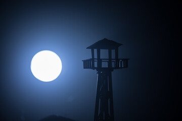 Creative artwork decoration. Silhouette of army watchtower at night. Selective focus