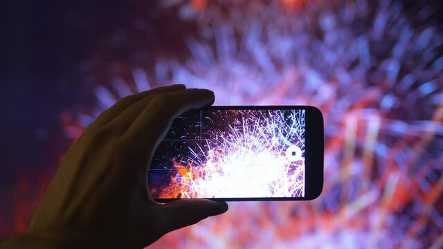 Person taking picture of the fireworks exploding show in 4K