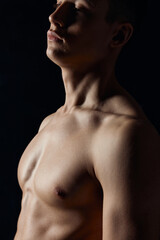 sexy bodybuilder with naked torso on black background portrait side view